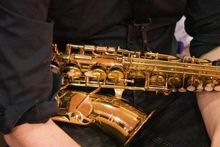 Foto van een saxofoon dat bij iemand op schoot ligt.