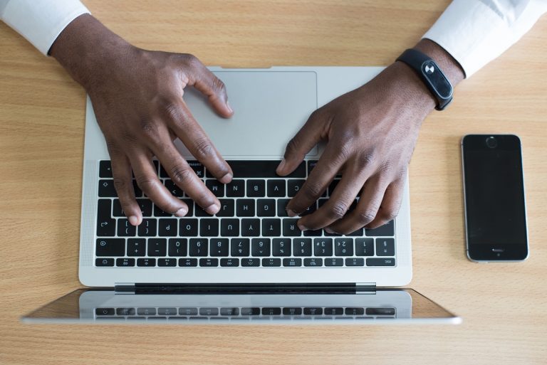 Twee handen aan het werk op een toetsenbord van een laptop