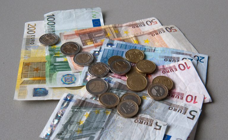 Verschillende eurobiljetten tussen de 5 en 200 euro met verschillende euromunten op een hoopje.