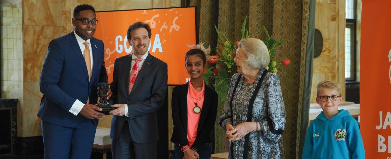 Op de foto krijgt wethouder Klijmij-Van der Laan de Jantje Betonprijs uitgereikt. Naast hem staan onder andere de kinderburgemeester va Gouda en prinses Beatrix.