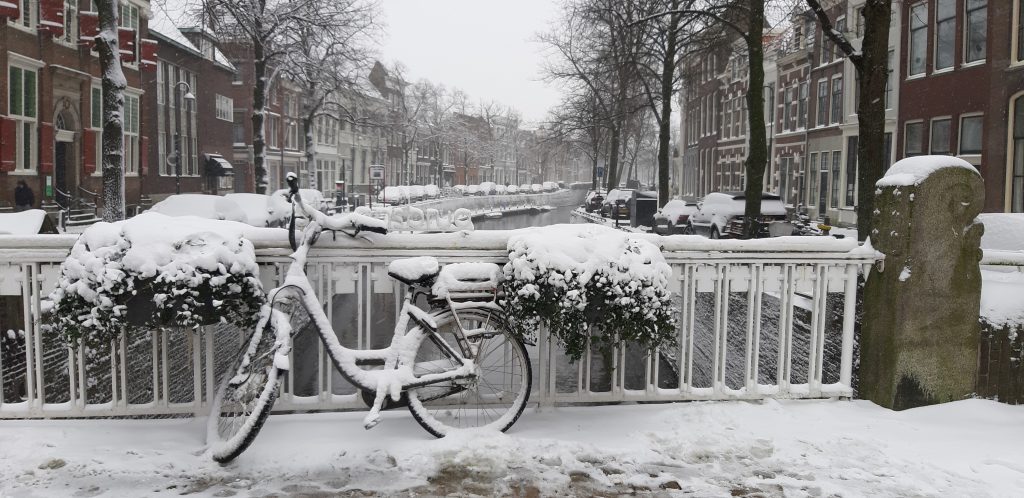 Foto van een fiets langs de gracht in de sneeuw