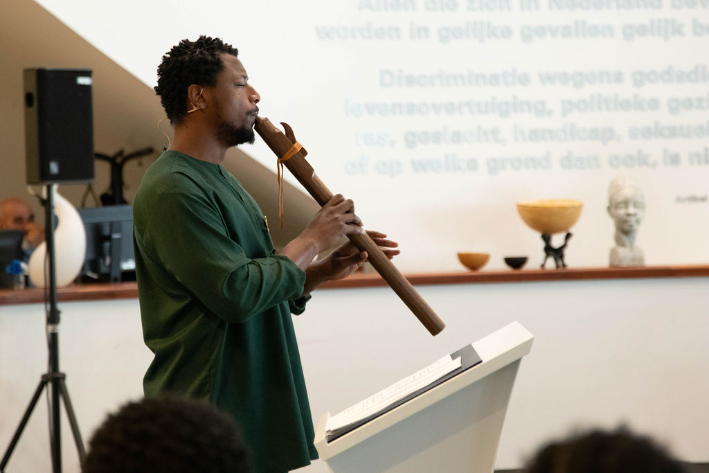 Romano Haynes speelt op de fluit in de hal van het Huis van de Stad.