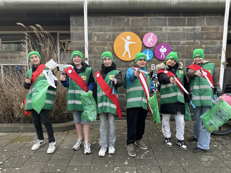 Mensen met groene hesjes aan en vuilniszakken in de hand