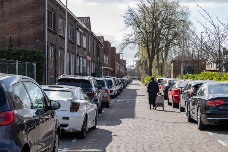 Op de foto is een straat in Gouda te zien met aan beide kanten veel geparkeerde auto's.