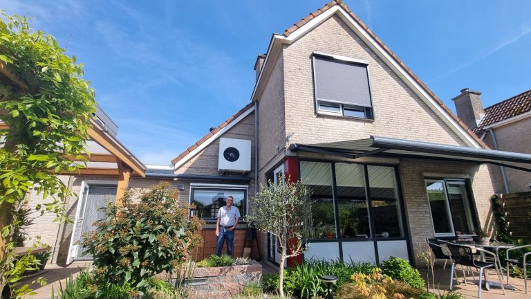 Een man poseert voor een woning