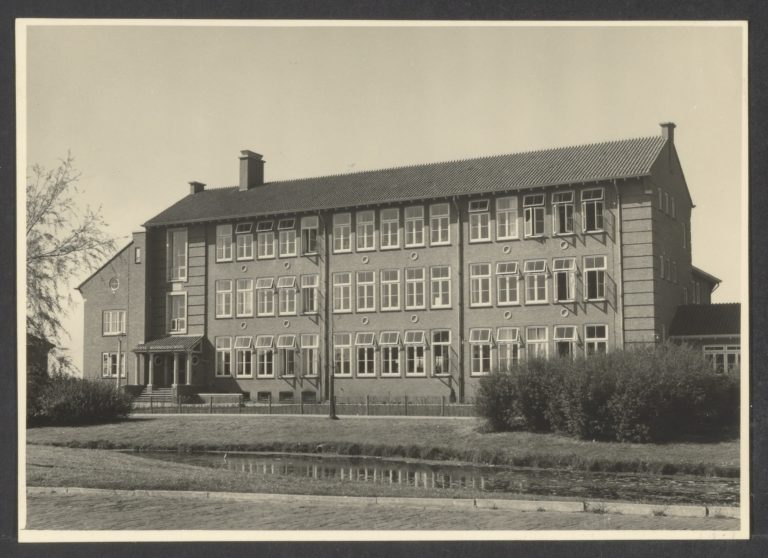 Op de afbeelding is een oude foto (uit 1955) van het Coornhert Gymnasium te zien