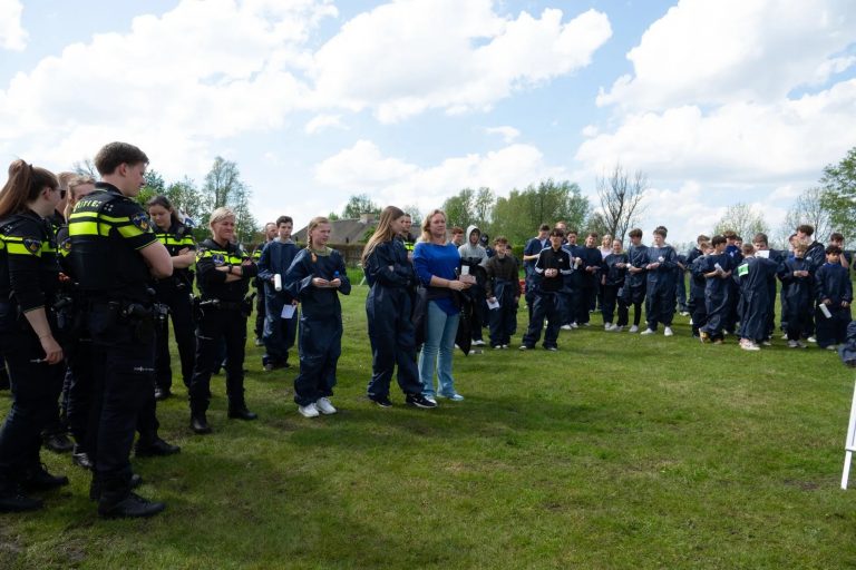 Jongeren in een blauw uniform staan op een grasveld, samen met politie.