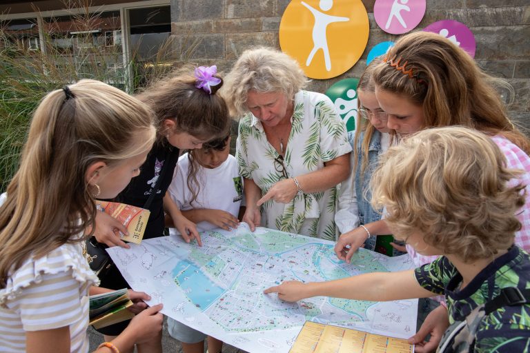 Wethouder Judith Sargentini kijkt met het Kindercollege naar de kaart met daarop alle speel- en sportplekken van Gouda.