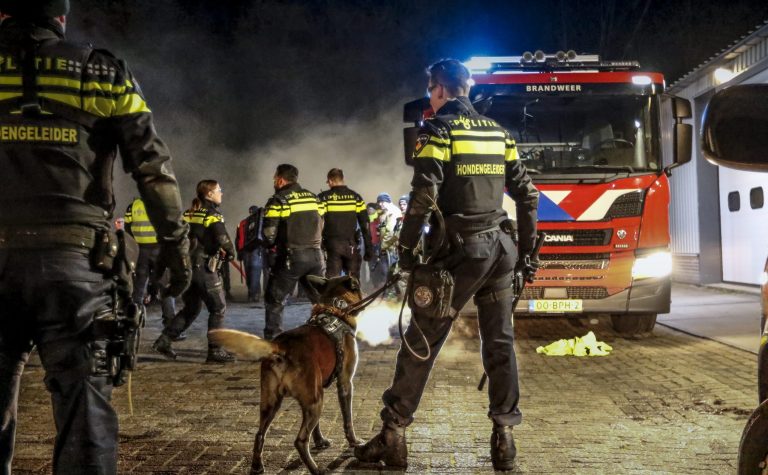 Verschillende politiemensen met een politiehond en een brandweerwagen