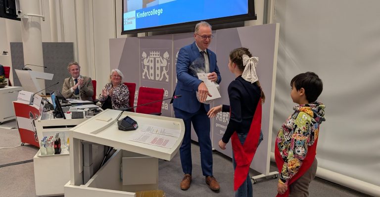 Kinderwethouders Adam en Lida overhandigen de uitslag van het kinderstemmen aan de Goudse gemeenteraad.