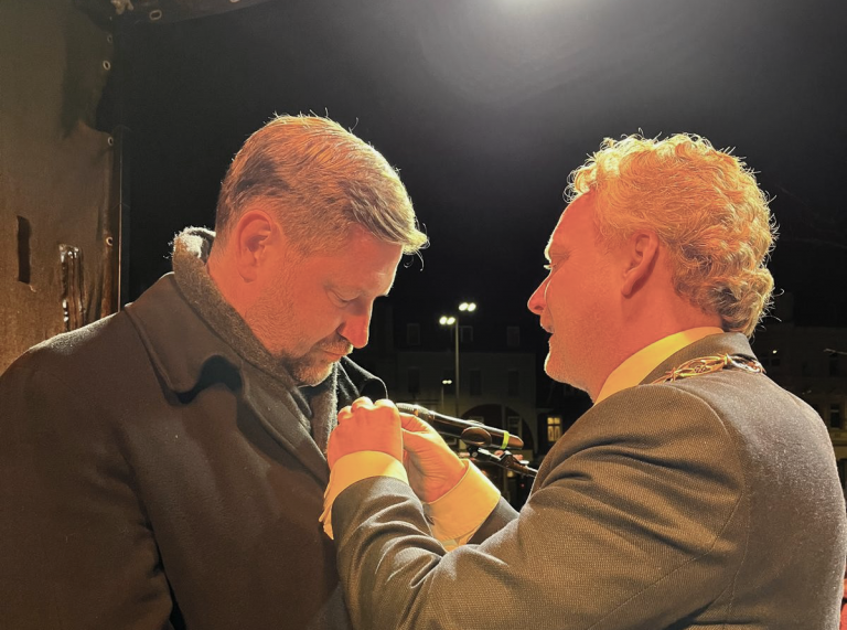 Burgemeester Pieter Verhoeven speldt de zilveren gemeentelijke erepenning op bij Tim Kurzbach.