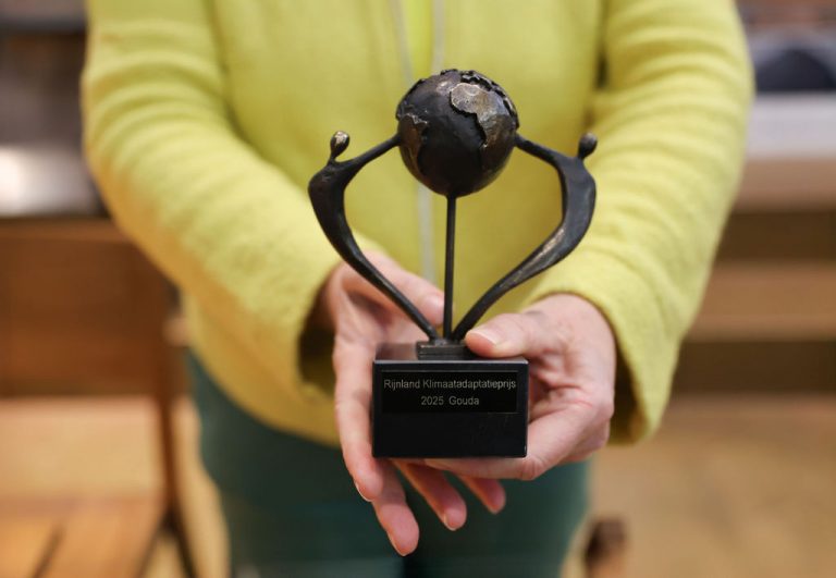 Wethouder Sargentini houdt de Klimaatprijs vast. Een ijzeren beeldje van twee mensen die samen de wereldbol vasthouden