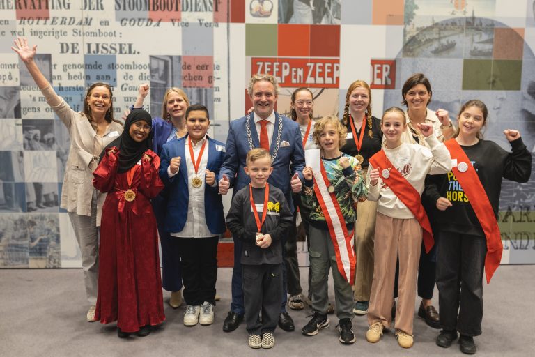 Bavly Shenouda, Sophie Fleur Anders, Riyan Osman, Saline Verkerk en Enzo Finlay Wolff de Jong staan samen met burgemeester pieter verhoeve en wethouder anna van popering-kalkman op de foto. De kinderen hebben een medaille om. Ook kinderwethouders Fenne Slingerland en Lida Kharytonova staan op de foto.