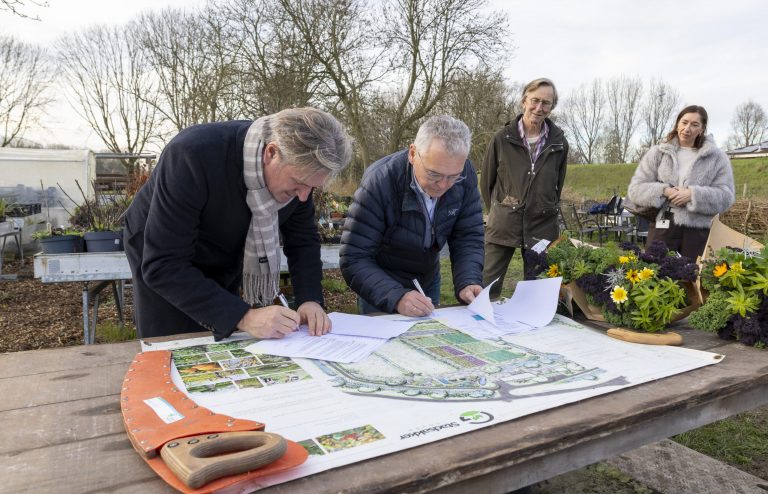 Wethouder Michel Bunnik en voorzitter van Stadsakker, Gert Olbertijn, ondertekenen een erfpachtovereenkomst.