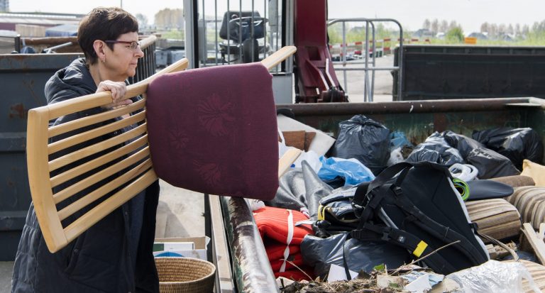 Mevrouw gooit een stoel in de afval container