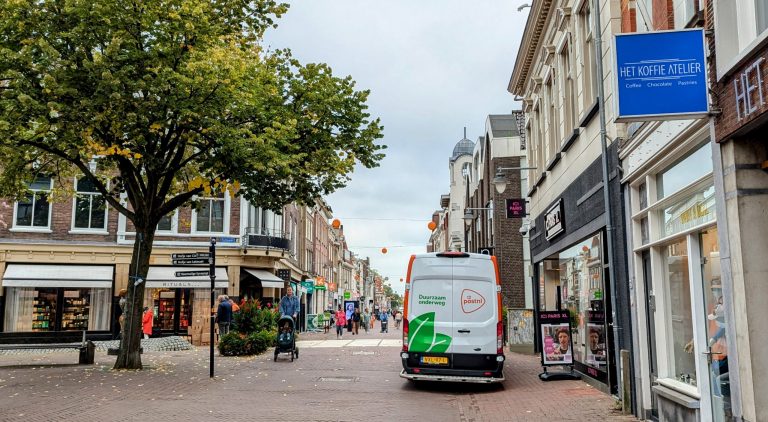 De Kleiweg met verschillende winkels en een bestelbus.