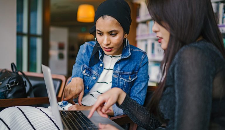 Afbeelding van 2 vrouwen die samen achter een laptop zitten.