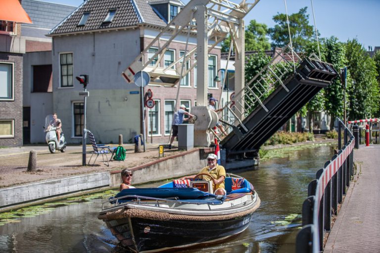 Een man vaart met een boot door de gracht