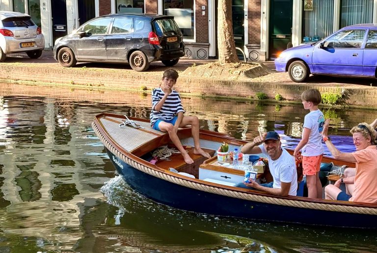 Een gezin vaart met een sloep door de binnenstad van Gouda tijdens de Langste ZaterWaterdag