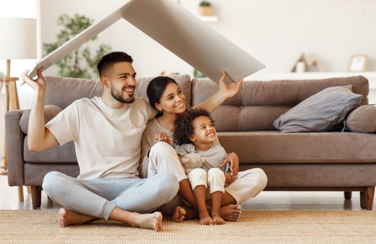 Man, vrouw en kind lachen en zitten op de grond van woonkamer