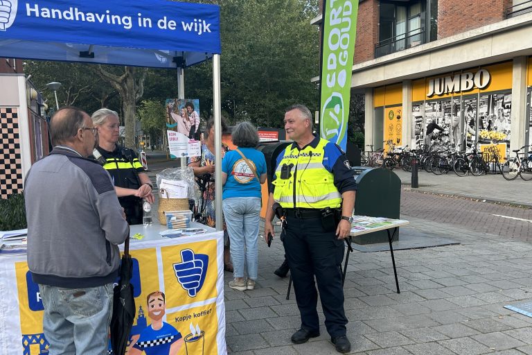 Foto van een handhaver en een politieagent die in gesprek is met een Goudse inwoner tijdens een wijkbezoek.